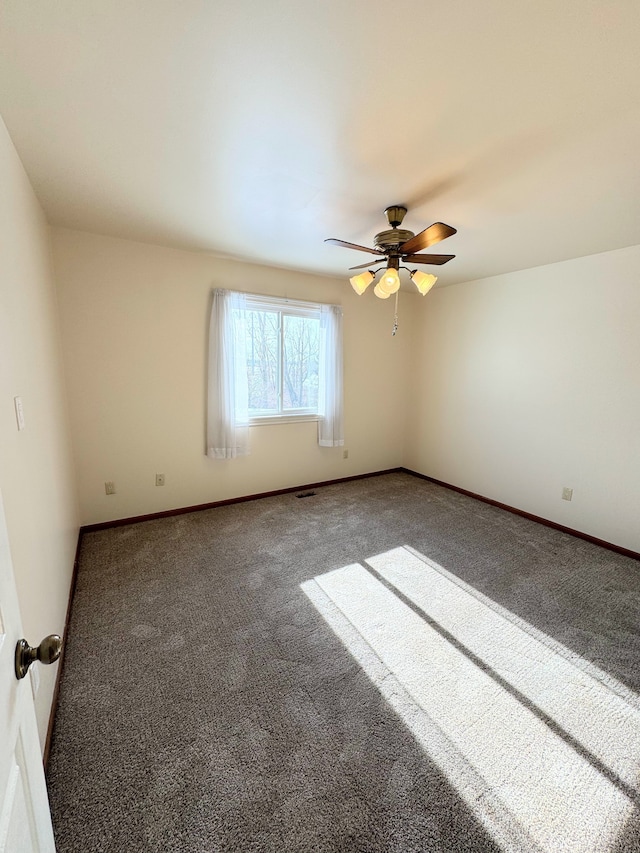 carpeted empty room with ceiling fan and baseboards