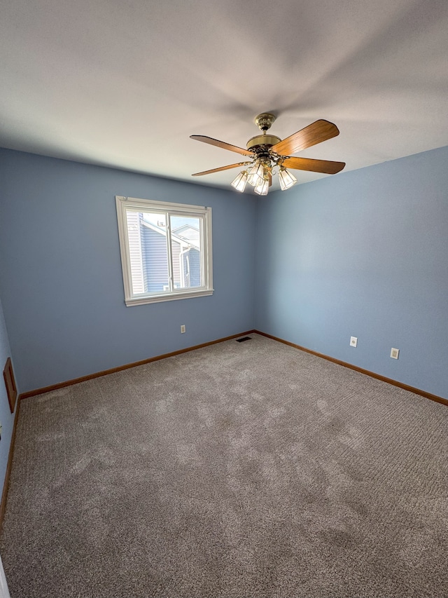 carpeted empty room featuring a ceiling fan, visible vents, and baseboards