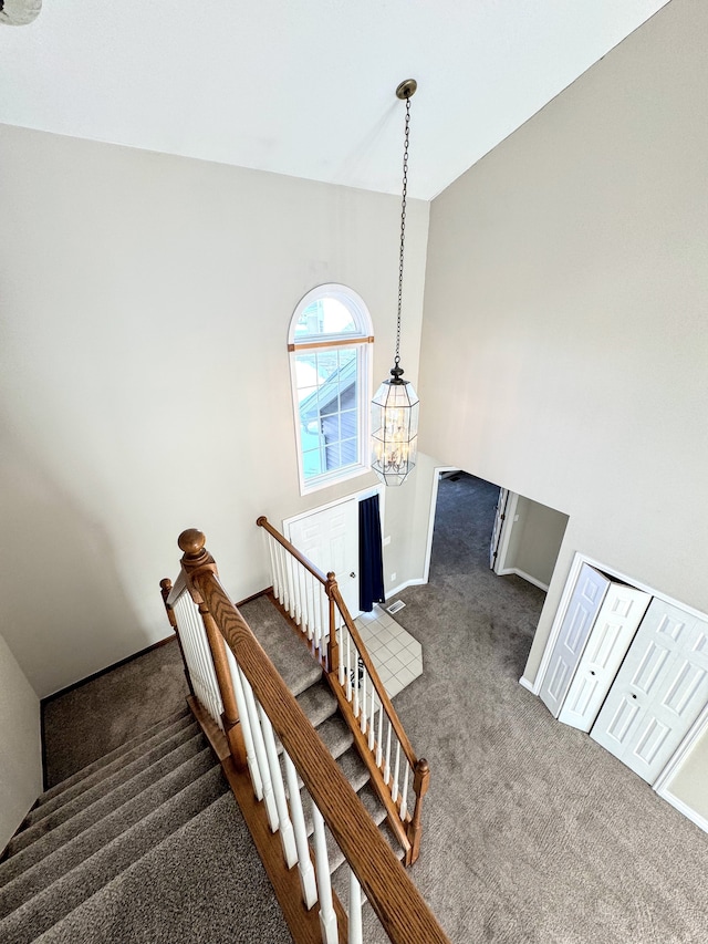 stairway with vaulted ceiling, carpet flooring, a notable chandelier, and baseboards