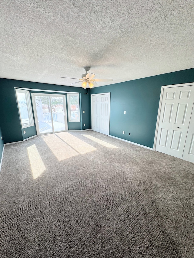 unfurnished bedroom with carpet floors, ceiling fan, a textured ceiling, and baseboards