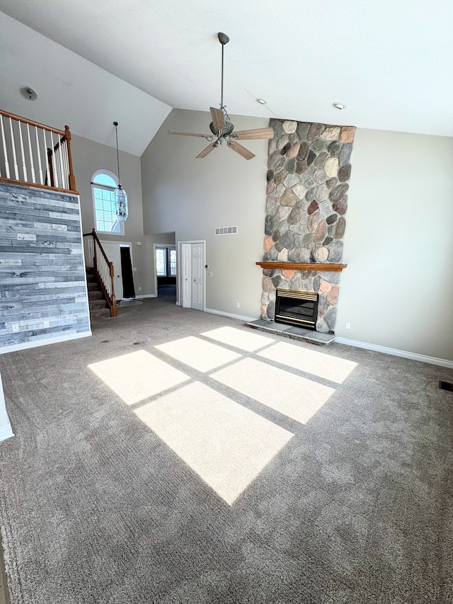 unfurnished living room with visible vents, stairway, carpet flooring, a fireplace, and high vaulted ceiling