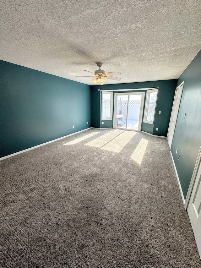 carpeted spare room with ceiling fan, a textured ceiling, and baseboards