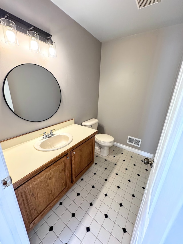 bathroom featuring baseboards, visible vents, toilet, tile patterned floors, and vanity