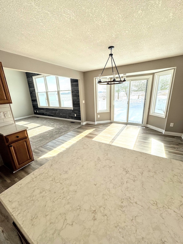 unfurnished dining area featuring baseboards, a chandelier, and wood finished floors