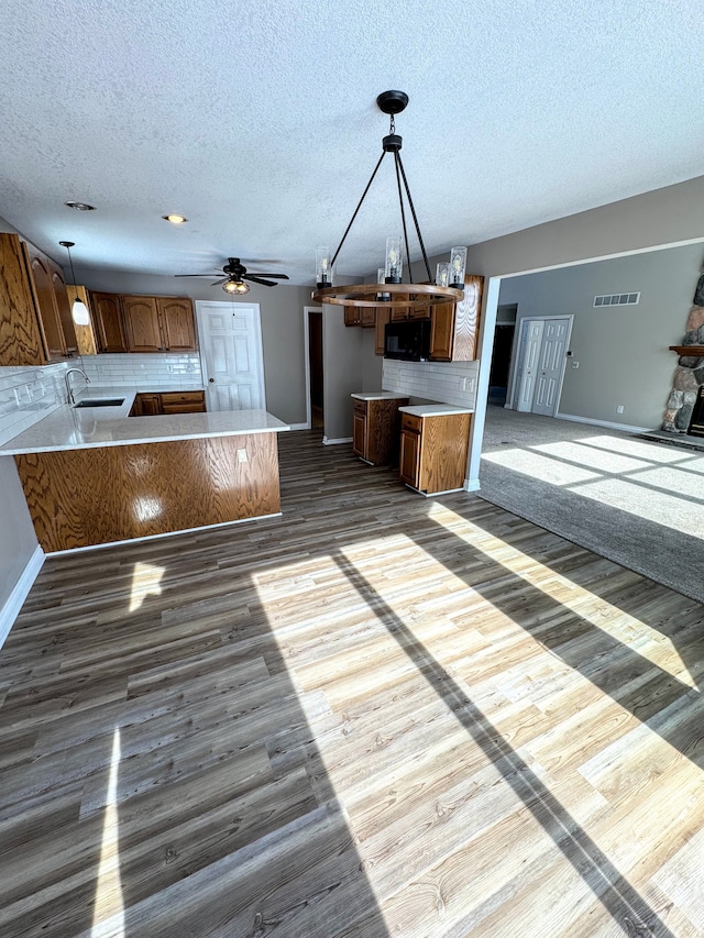 kitchen with brown cabinets, light countertops, backsplash, open floor plan, and a peninsula