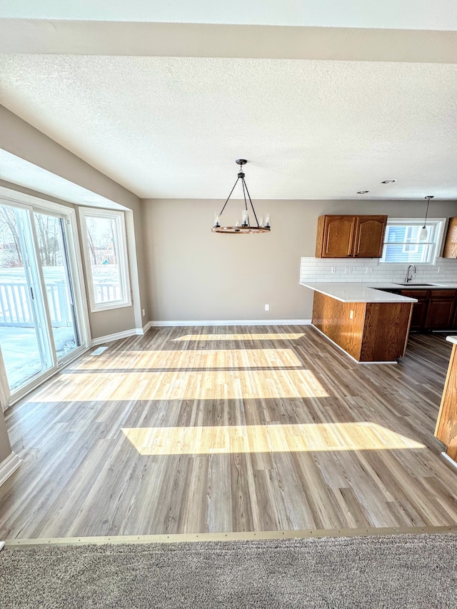 kitchen featuring a sink, light wood-style floors, light countertops, backsplash, and an inviting chandelier