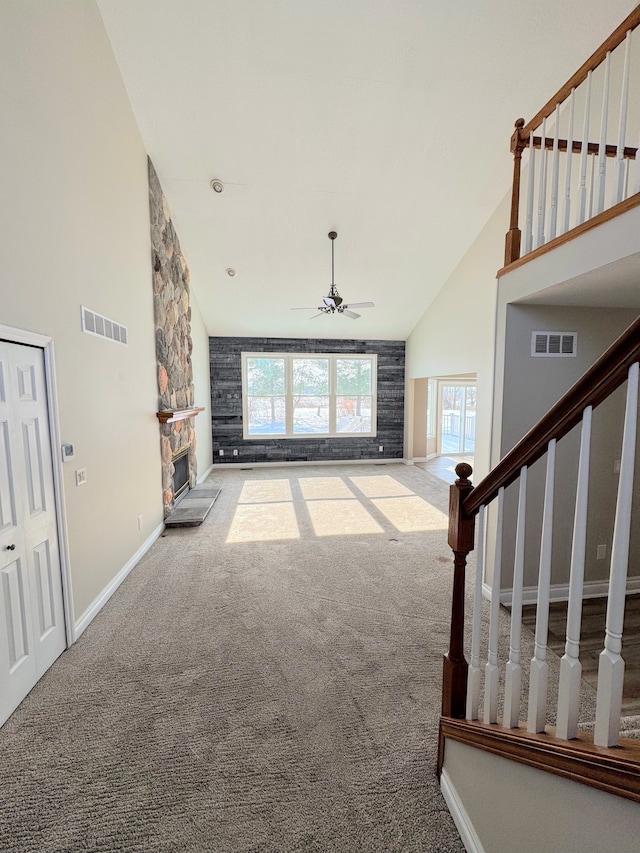 unfurnished living room featuring high vaulted ceiling, a fireplace, visible vents, and carpet flooring