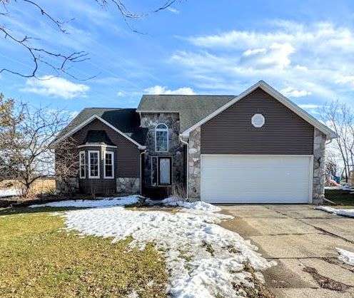 view of front facade with driveway, stone siding, and a garage