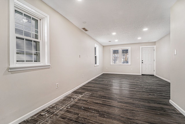 empty room with recessed lighting, visible vents, dark wood-type flooring, a textured ceiling, and baseboards