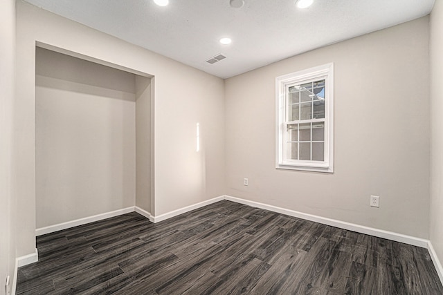 spare room featuring dark wood-type flooring, recessed lighting, visible vents, and baseboards