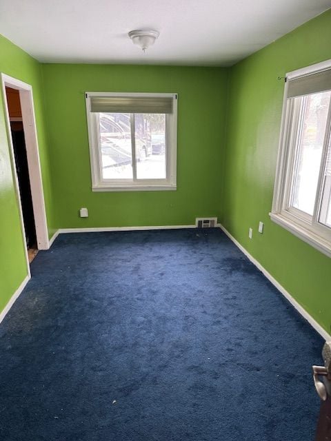 spare room with carpet, visible vents, and baseboards