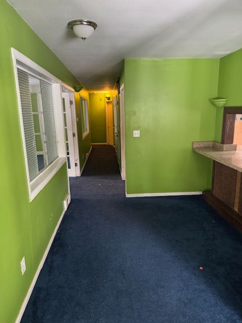 hall featuring carpet and baseboards