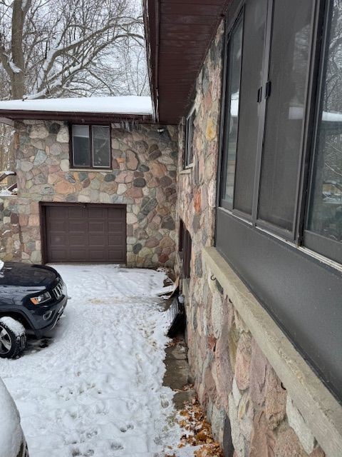 view of snow covered exterior featuring stone siding