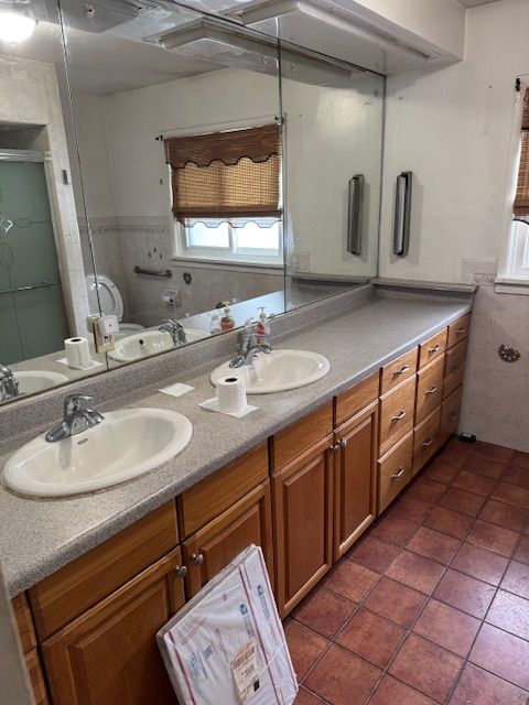 full bathroom with a sink and double vanity