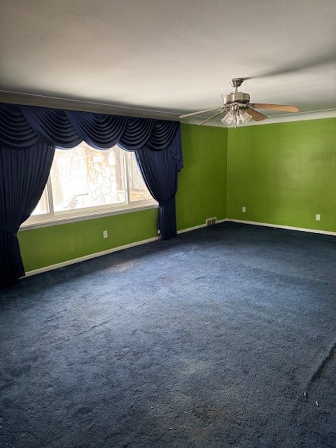 unfurnished room featuring a ceiling fan, visible vents, baseboards, and carpet flooring