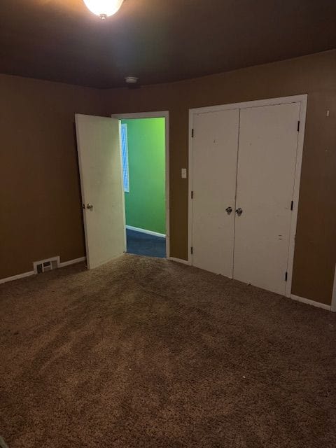 unfurnished bedroom featuring carpet floors, a closet, and visible vents