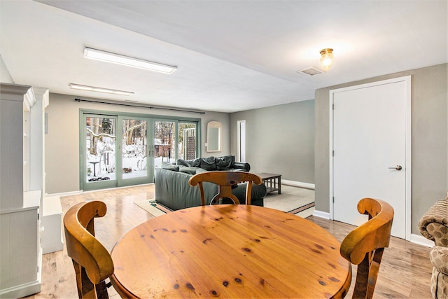 dining space with light wood-style flooring, visible vents, baseboards, and french doors