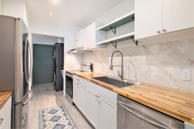kitchen with stainless steel appliances, a sink, wooden counters, and white cabinetry
