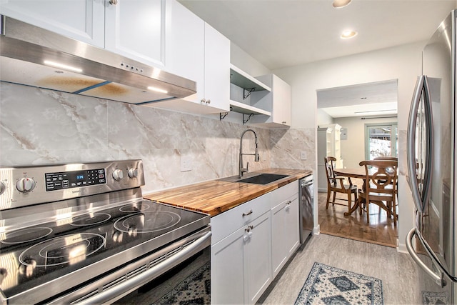 kitchen with light wood-style flooring, under cabinet range hood, stainless steel appliances, a sink, and open shelves