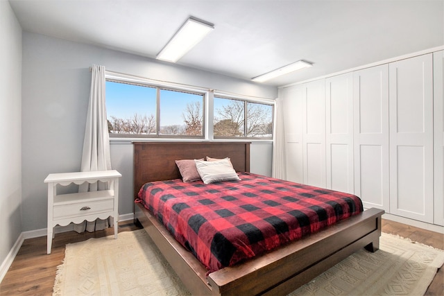 bedroom with light wood-type flooring, a closet, and baseboards