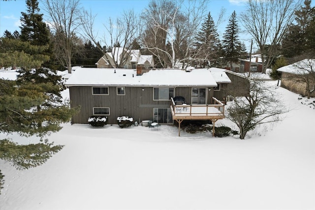 snow covered property featuring a chimney and a wooden deck