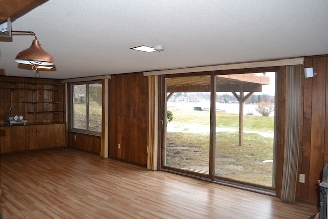 unfurnished living room with a healthy amount of sunlight and wood walls