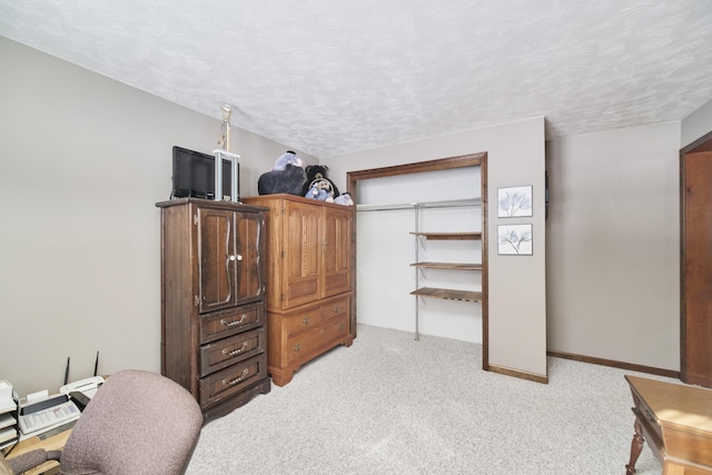 bedroom featuring light colored carpet, a textured ceiling, and baseboards