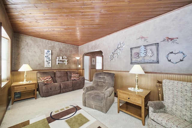 living area featuring arched walkways, wainscoting, carpet flooring, and wood ceiling