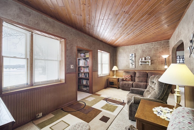 living room with light carpet, a wainscoted wall, wood ceiling, and wallpapered walls