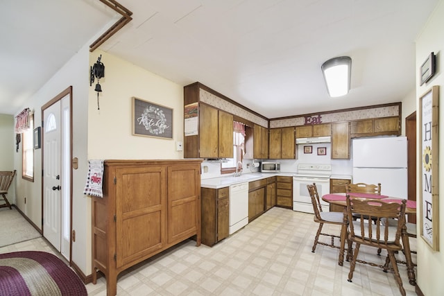 kitchen featuring light floors, light countertops, brown cabinetry, white appliances, and under cabinet range hood