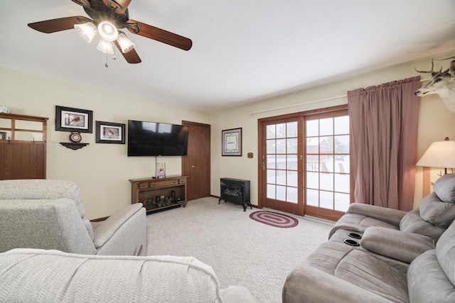 living area featuring a wood stove, ceiling fan, and light carpet