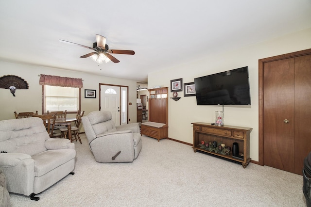 living area featuring ceiling fan, baseboards, and light colored carpet