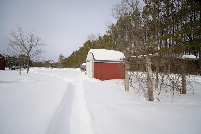 snowy yard with an outdoor structure and a barn