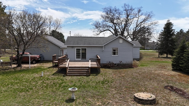 back of house featuring a lawn, a deck, and roof with shingles