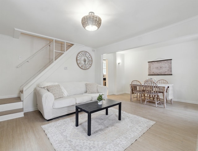 living room featuring light wood finished floors, stairs, and baseboards