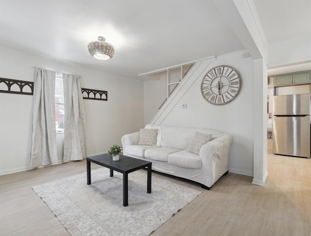 living area featuring ornamental molding, baseboards, and light wood finished floors