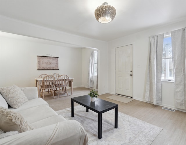 living room featuring arched walkways, visible vents, light wood-style flooring, and baseboards