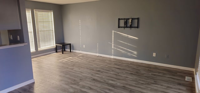 spare room with dark wood-style flooring, visible vents, and baseboards