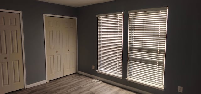 unfurnished bedroom with light wood-style flooring, baseboards, and a closet