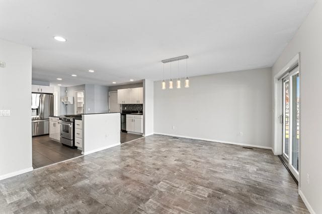 unfurnished living room with baseboards, dark wood-type flooring, and recessed lighting