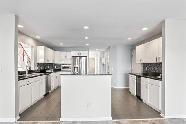 kitchen featuring appliances with stainless steel finishes, dark countertops, white cabinetry, and a center island