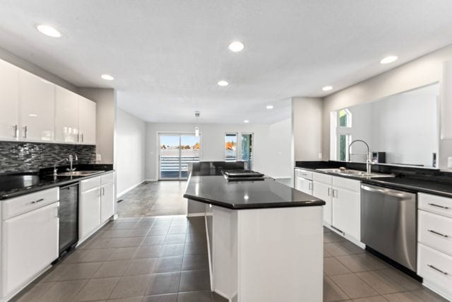 kitchen featuring dark countertops, a center island, white cabinetry, and dishwasher