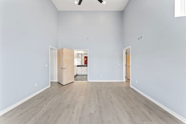 interior space featuring light wood-style floors, visible vents, baseboards, and a ceiling fan