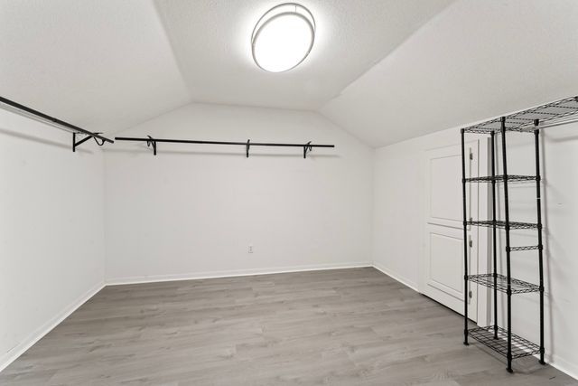 spacious closet with lofted ceiling and wood finished floors