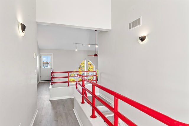 corridor with baseboards, dark wood-type flooring, visible vents, and track lighting