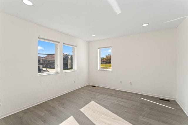 unfurnished room with visible vents, baseboards, dark wood-style flooring, and recessed lighting