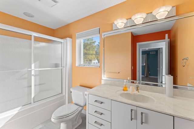 full bath with toilet, enclosed tub / shower combo, visible vents, and vanity