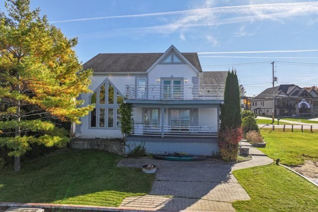 tudor home with a balcony, stucco siding, and a front yard