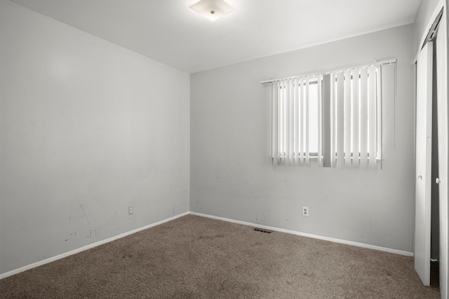 carpeted empty room featuring baseboards and visible vents