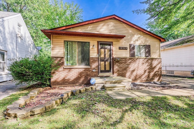 bungalow-style home with brick siding and fence